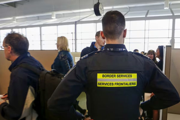 مأمور مرزی در حال بررسی مدارک مهاجرتی مسافر، یکی از مراحل تأیید یا رد ویزا.