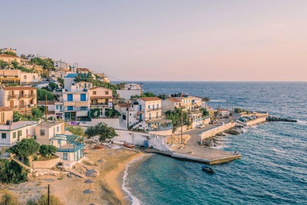 نمایی از خانههای ساحلی و اسکله جزیره ایکاریا در یونان هنگام غروب، با آبهای آرام دریای اژه - یونان چند جزیره دارد