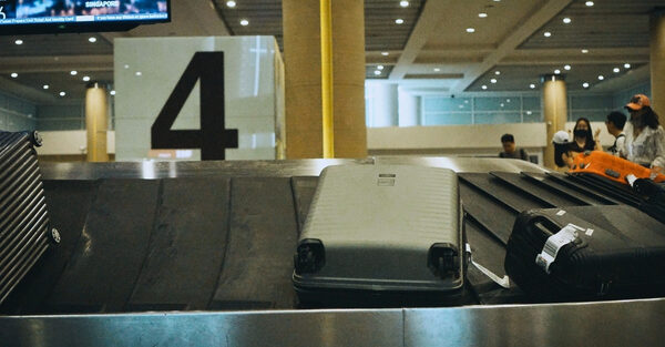 چمدان‌های روی نوار نقاله فرودگاه در بخش تحویل بار، مرتبط با اضافه بار هواپیما و محدودیت‌های بار مجاز در سفرهای بین‌المللی.
